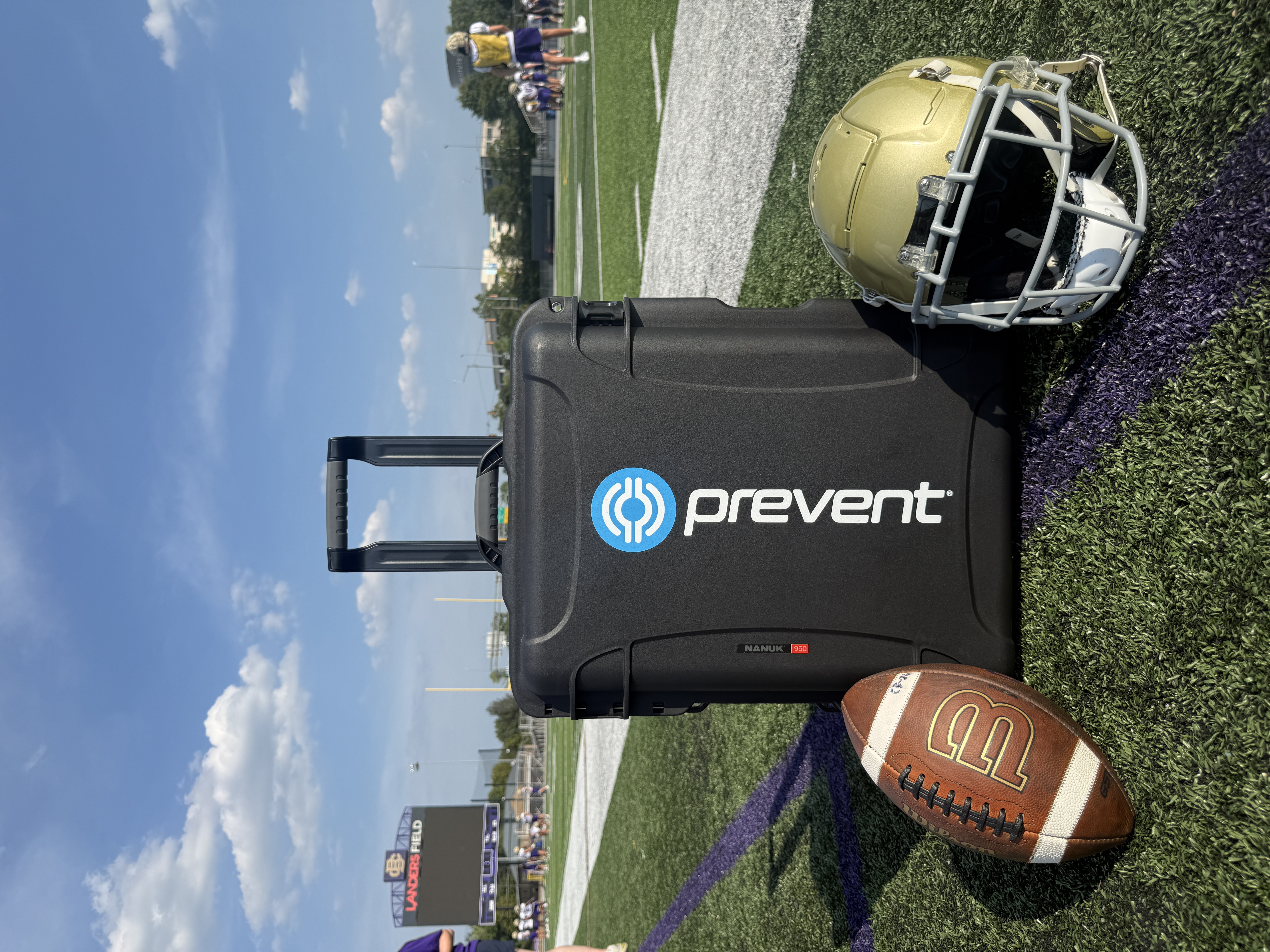 Prevent case, football and helmet on a high school practice field